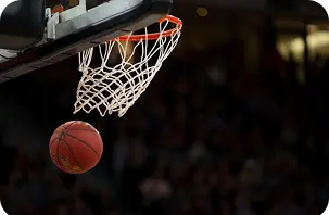 Imagem de desportos de ação capturando uma bola de basquetebol perto da rede numa arena competitiva.